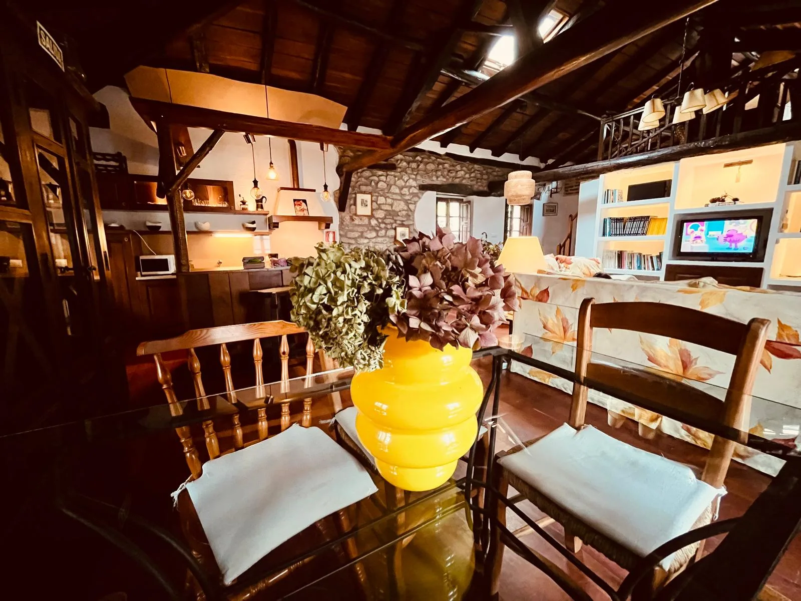 Comedor abierto a la cocina rústica con vigas de madera
